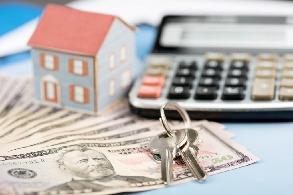 Money, Calculator, House Miniature and House Keys on the table