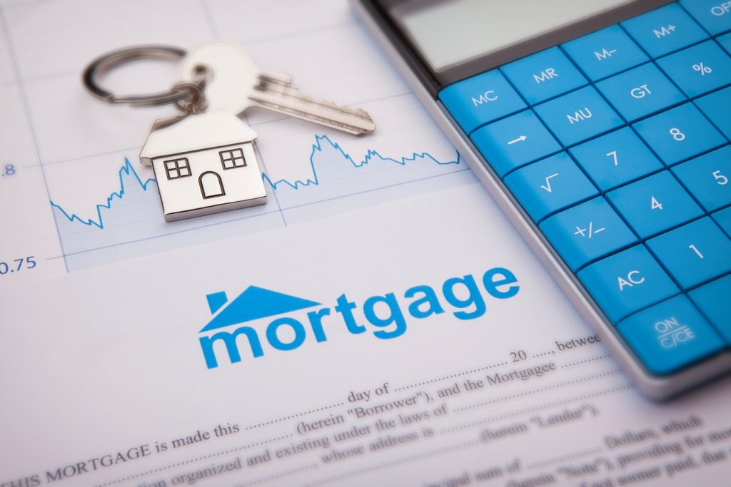 A house key and calculator on top of mortgage contact
