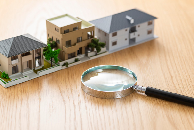 Small house models and a magnifying glass on a wooden table