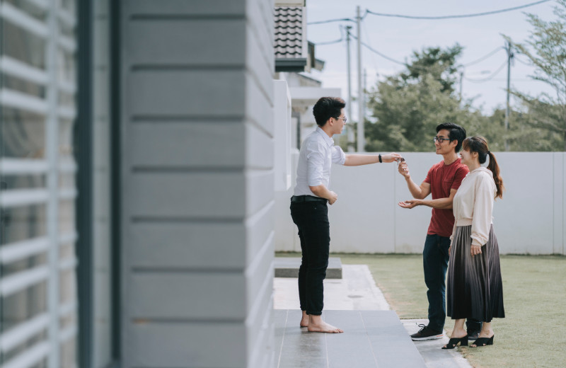 An Asian real estate agent handing over the keys to an Asian couple